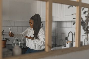 African american woman making video call in kitchen - social networks and connection