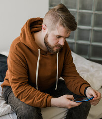 Freelance man using mobile phone checking social media network feed or message chat at home. Online digital communication and rest after hard work day