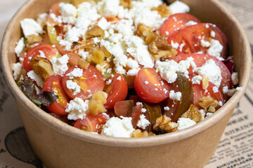 Close-up of tomato salad with cheese in a cardboard takeout container. Food and healthy concept