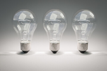 three retro style lightbulbs with glowing filament standing in a row on infinite colorful background; creativity design concept; 3D Illustration