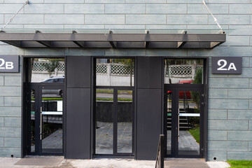 The front door of a office block, reflecting buildings in the glass