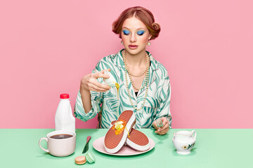 Beautiful young girl with makeup and hairdo having breakfast with surreal sneakers waffles with...