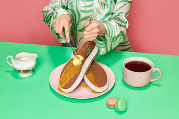 Female hands cutting with fork and knife surreal waffles sneakers with melting butter and honey...