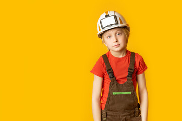 Portrait of blond teenage boy in white helmet and work overalls on yellow background. Mock up, copy space.