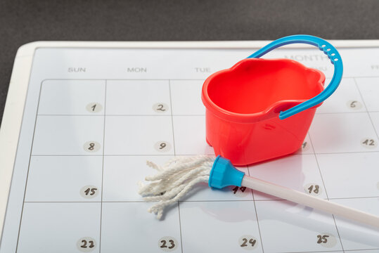 Toy bucket and mop on calendar background. Concept of spring general cleaning. Planned cleanup.