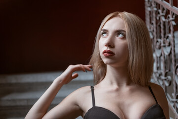 Portrait of fair-haired young woman in the top with plunging neckline inside. Sexy blonde model in...