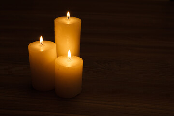 Fototapeta na wymiar three burning candles in the semi-darkness