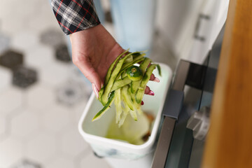 Female hand put compostable food peels in a bokashi bin for fermentation