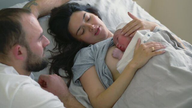 Woman and man look with smile at newborn baby in ward