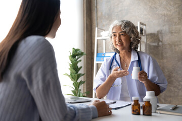 Asian Senior elderly female patient consult with physician nurse at nursing home care. Caregiver therapist pharmacist girl hold medicine pills bottle
