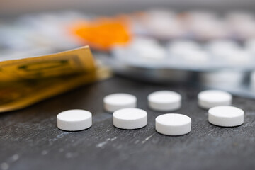 White round pills, blister packs with tablets, antibiotic, painkiller or drugs and money, US dollar banknotes, expensive medicine and healthcare concept, close-up view