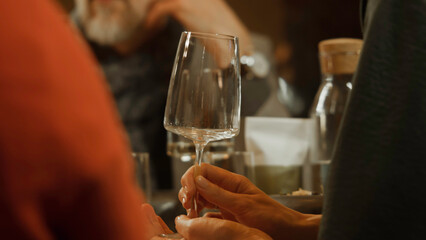 Close up shot of female hands holding glass of white wine in restaurant. Birthday celebration, family dinner, spending leisure time or weekend evening in modern gastro cafe. Concept of public eating.