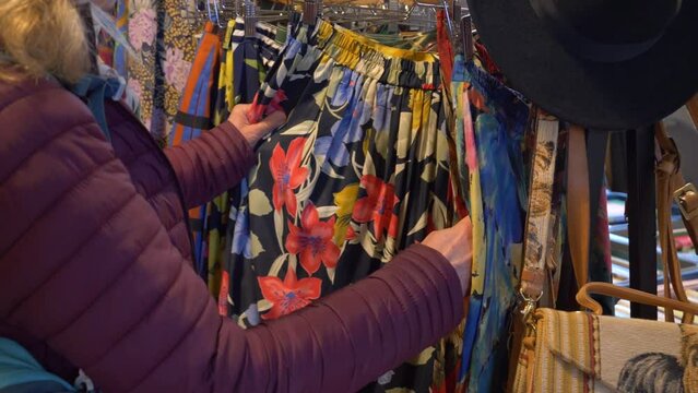 The customer is looking at colorful pants at an antique market