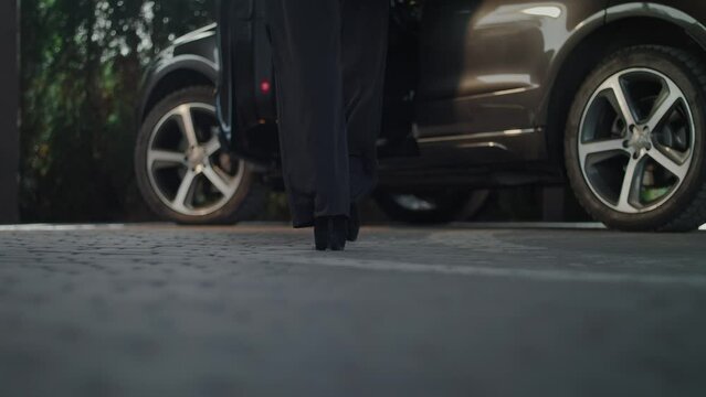 The camera is on the ground showing us the view from below. We see a close-up of a woman�s legs. She wears high heels and gets inside her car. The camera stays on the ground.