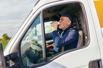 Truck driver drinks canned juice while sitting in the white cargo van vehicle