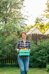 Organic female farmer holding box full of fresh produce on her farm copy space and empty place for text. Happy young woman smiling at camera while standing in her vegetable garden. Successful female