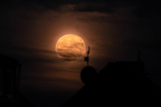 Moon glowing in the night sky in front of a silhouette of a church