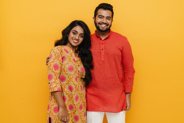 Indian man and woman hugging and smiling at camera while stading isolated over yellow background