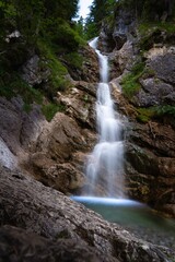 Vertical long exposure shot of a beautiful waterfall in the Bavarian Alps, Germany