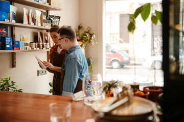 Woman training man with down syndrome to work as barista in coffee shop