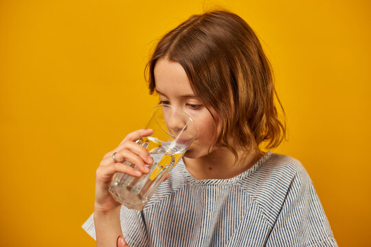 Pretty teen girl, child with a fresh glass of water isolated