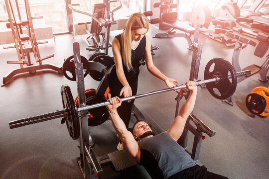 Young couple doing barbell exercises in the gym together. Wide angle shooting, top view.