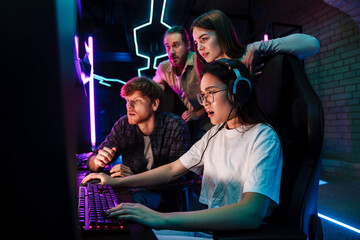 Group of people watching their friend playing video game in cybersport club