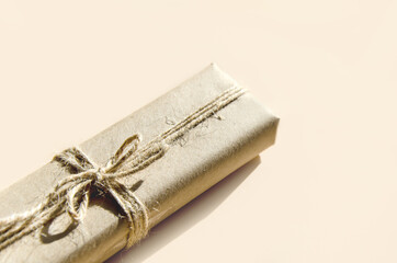 gift box in kraft paper and tied with twine on beige background. Vintage box made of brown eco-paper