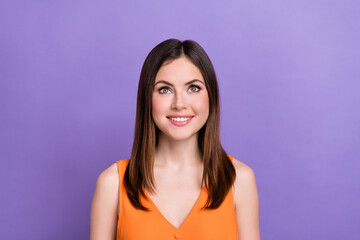 Portrait of charming cheerful lady beaming smile look up above empty space isolated on purple color background