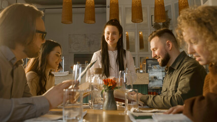 Waitress talks with guests and serves group of friends or relatives. People watch menu, talk with female worker and make order. Celebrating anniversary, birthday or family dinner in modern restaurant.