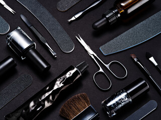 A monochrome photo of beauty manicure tools, such as nail files, clippers, nail polish and brushes with a black background. Beauty procedures at home or salon visit. Wellbeing, self treatment concept.