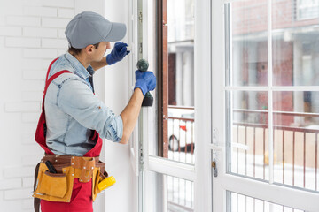 Construction worker installing window in house. Handyman fixing the window with screwdriver