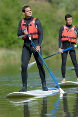 man on paddle board paddling out to lake