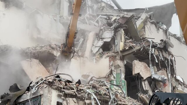 Natural disasters, demolition of a building in a residential area, hydraulic claw of excavator demolishing the building after earthquake.