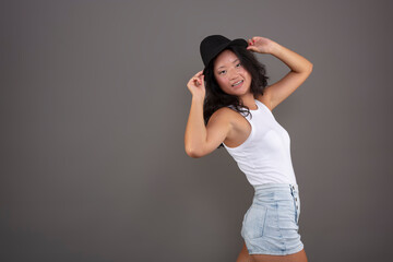 cute asian ethnic woman, posing in shorts, tank top and hat