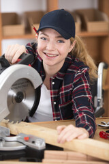 happy young lady in a wheelchair using a circular saw