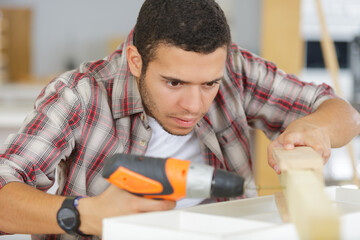man drills the wooden plank