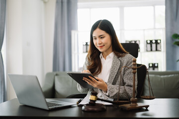 Asian lawyer woman working with a laptop and tablet in a law office. Legal and legal service concept. Looking at camera