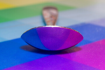 Abstract shot of a teaspoon reflecting colourful harlequin pattern. Graphic resource.