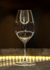 Vertical shot of an empty wine glass on the yellow illuminated table
