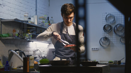 Male chef in apron pours oil in frying pan on stove, puts pieces of beef meat. Process of preparing...