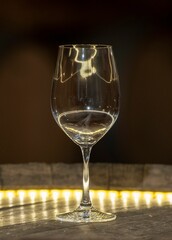 Vertical shot of an empty wine glass on the yellow illuminated table