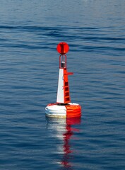 Vertical of a fairway buoy on reflective water during sunrise