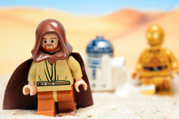 Fototapeta premium Lego Star Wars figure Obi Wan Kenobi togehter with Androids R2-D2 and C-3PO on the desert planet Tatooine