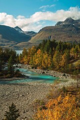 Winding river lined with trees at against a mountain
scenery in the background in Lyngen, Norway