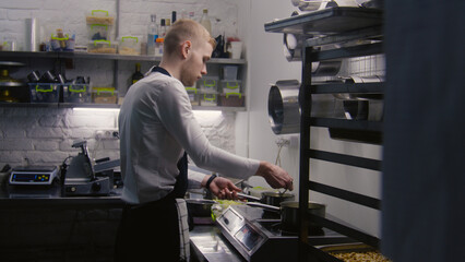 Chef and sous chef cook delicious meal. Male cooks work together on kitchen, make sauce or soup in...