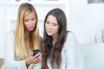 two beautiful girls looking on phone are surprised