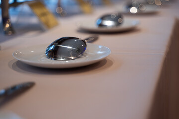 Silver spoons laying on an empty plate on a beige background side view Dining table in a luxury restaurant