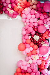 Arch with balloons, flowers for party. White photo wall decoration space or place with pink, red, maroon, burgundy balloons. Trendy spring decor. Celebration concept. Birthday party. Wedding reception