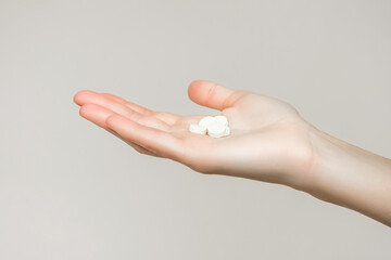 a woman holds a handful of white round pills in her palm